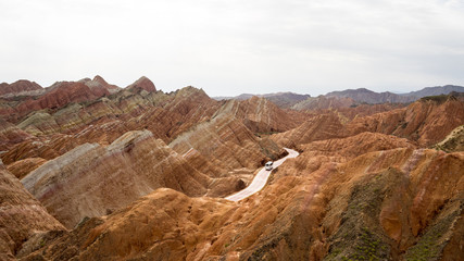 Fototapeta na wymiar The bus is riding in the middle of rainbow mountains of china (Zhangye Danxia landform Geological park), Zhangye, Gansu province, which was named a UNESCO world heritage site in 2009.