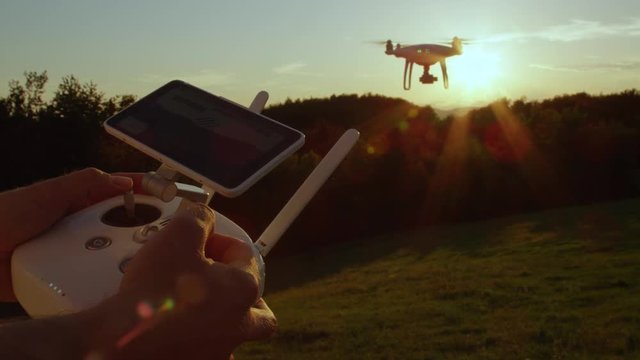 SLOW MOTION CLOSE UP: Man's hands flying quadro drone with modern white RC transmitter. Unrecognizable person controlling drone over RC radio controller. Man flying and filming with drone camera