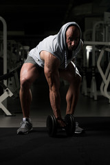Obraz na płótnie Canvas Bodybuilder Exercising Biceps With Dumbbells