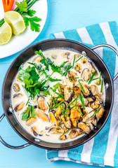 Mussels in creamy milk sauce with aromatic herbs and lemon. Top view Blue background. Top view