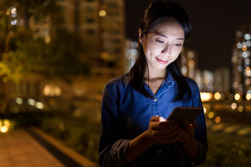 Woman looking on cellphone in the city at night