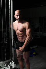 Fototapeta na wymiar Bodybuilder Doing Heavy Exercise For Shoulders With Cable