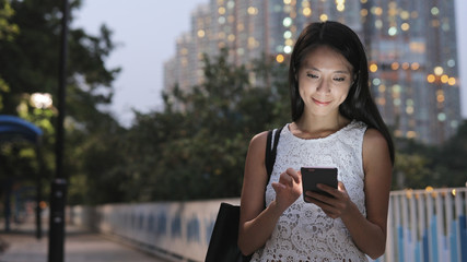 Woman use of cellphone in city at night