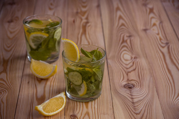 Detox water, fresh organic lemonade with ice, cucumber, lemon and mint on wooden background
