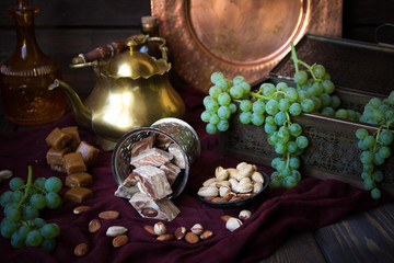 Traditional oriental sweets, nuts and grape. Metal and copper kitchen tools