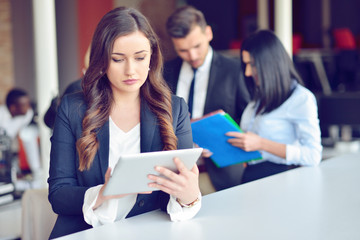 Confident attractive young business woman with tablet in hands in modern office start up office