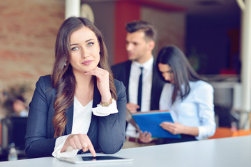 Confident attractive young business woman with tablet in hands in modern office start up office