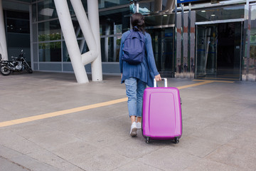 Woman traveller with travel suitcase or luggage walking in airport terminal 