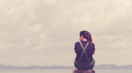 The girl sitting alone lonely at the sea. With loneliness