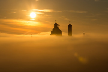 Landscape: Church silhouette floating in the clouds at dawn.