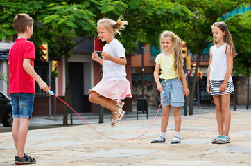 Kids in school age playing together with jumping rope