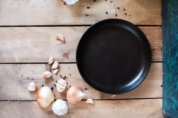 Eggplants on paper. Black cast-iron frying pan. Pepper black peas and garlic. Greens for cooking. The process of cooking.