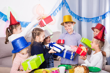 children giving presents to little boy during party