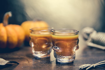 Ideas for a children's and party of Halloween treats. Pumpkin orange cocktail in glasses, decorated with a pumpkin jack lantern, skelaton on a black wood table. Copy space