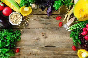 Vegetables on wooden background. Herbs, basil, onion, pumpkin, pine nuts, tomatoes, corn, radish, eggplant, bell pepper, salt, spices, oil, spinach, parsley, lettuce leaves. Top view, copy space