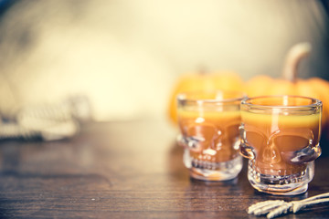 Ideas for a children's and party of Halloween treats. Pumpkin orange cocktail in glasses, decorated with a pumpkin jack lantern, skelaton on a black wood table. Copy space
