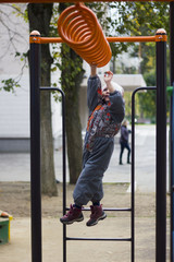 Little girl playing on playground, hanging walk along the monkey bars