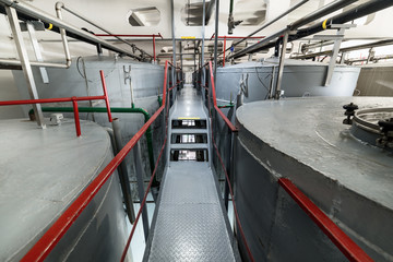 Narrow and long staircase between large tanks. Large steel cylindrical tanks for fermenting the yeast mixture.