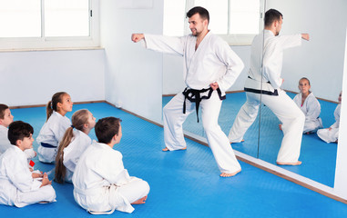 Coach showing new martial moves to children in karate class © JackF