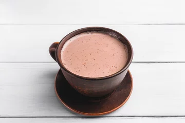 Gordijnen Warme chocolademelk met melk in bruine kleikop, op tafel van witte houten planken © O.Farion