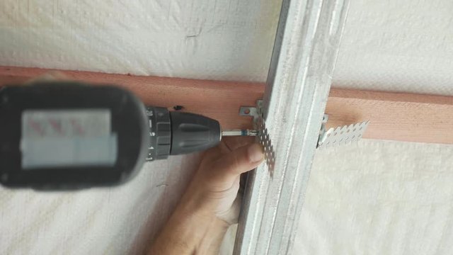 Worker mounting metal construction for drywall in a newly built house