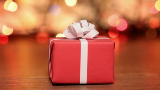 Dolly shot of red present box against blurry lights - gift for christmas or other events