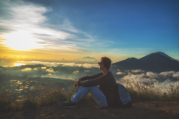Fototapeta na wymiar Man watching the sunrise from mount Batur, Bali - Indonesia.