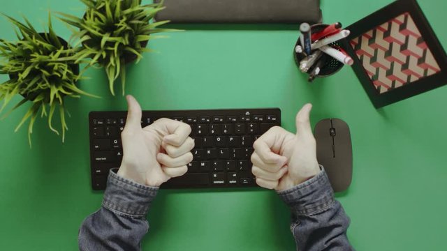 Top view shot of man using keyboard and showing thumbs with chroma key on background