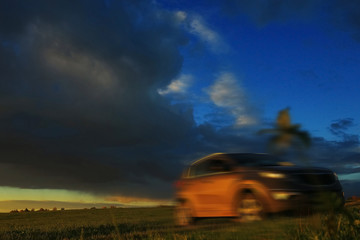 Fototapeta premium Car in the field at sunset