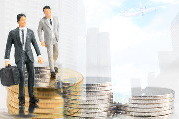 Miniature success young businessman stand on coins with big city and air plane background