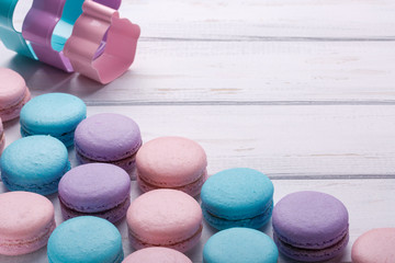 Sweet colorful macaroons on white wooden background. Space for text