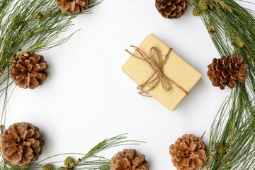 Christmas ornamate brown gift box and pine cones fresh green branch on white background,flat lay