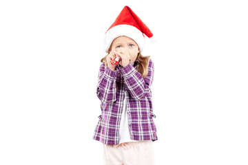 Portrait of sweet little girl in Santa hat blowing into party blower