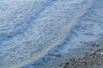 Waves moving along the dioganal with sea foam. Close-up. Texture. Horizontal