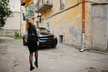 Fototapeta na wymiar Elegant blonde girl wear on black leather jacket posing at streets of town background luxury car.