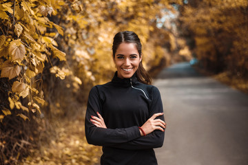 Portrait of female athlete in autumn park.