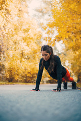 Fitness woman doing pushups in autumn park. © bnenin