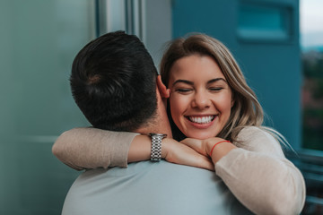 Beautiful lady leans to man's shoulder while he hugs her.