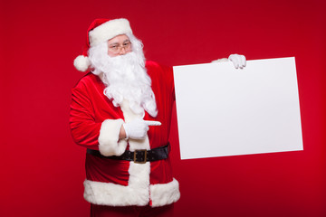 Santa Claus pointing in blank advertisement banner isolated on red background with copy space