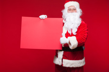 Santa Claus pointing in blank advertisement banner isolated on red background with copy space red leaf