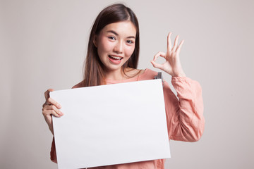 Naklejka premium Young Asian woman show OK with white blank sign.