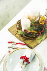 a table setting for Christmas with a viburnum on a plate and an ornament from a Christmas wreath with candles