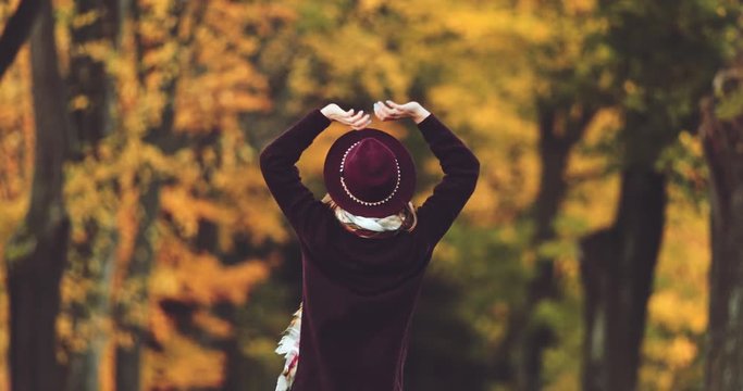 Young Woman Enjoying Autumn Outdoors. SLOW MOTION 4K. Calm relaxed woman standing in the colourful fall mountain forest, on the scenic road. Cinematic shot. Freedom and authentic life concept. 