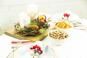 a table setting for Christmas with a viburnum on a plate and an ornament from a Christmas wreath with candles
