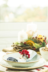 a table setting for Christmas with a viburnum on a plate and an ornament from a Christmas wreath with candles
