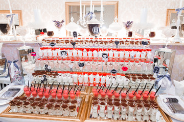 Delicious and tasty dessert table with cupcakes shots at reception closeup