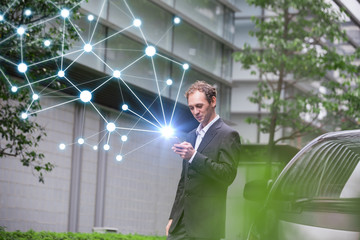 Middle aged businessman calling with smart phone beside of a car.