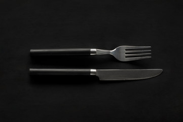 black knife and fork on a dark background