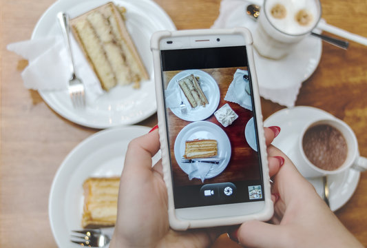 The girl takes pictures of breakfast on the phone in the Instagram.