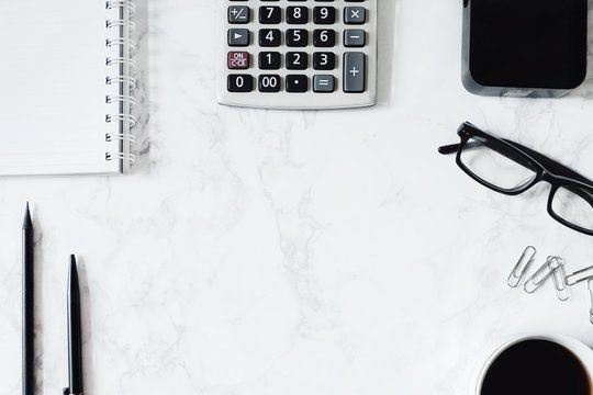 Business Desk Composition. Notebook, Pen, Pencil, Power Bank, Calculator, Glasses, Paperclip, Hot Coffee On Marble Table. Desk For Businessman Working Concept. Flat Lay, Top View. B&W Tone. Copy Space